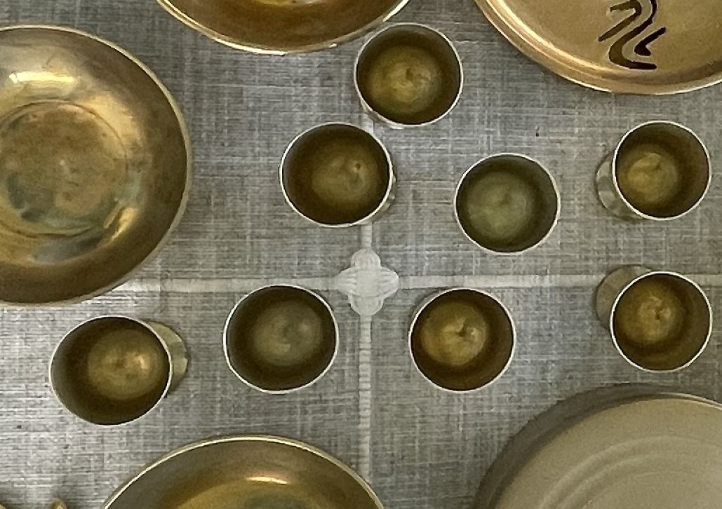 Brass drinking set: nine small cups, stemmed goblets, footed bowls and drip pans
